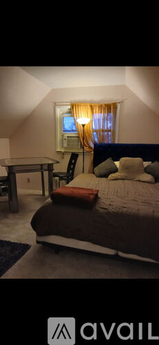 A bedroom with a bed, a table, and a window with curtains.