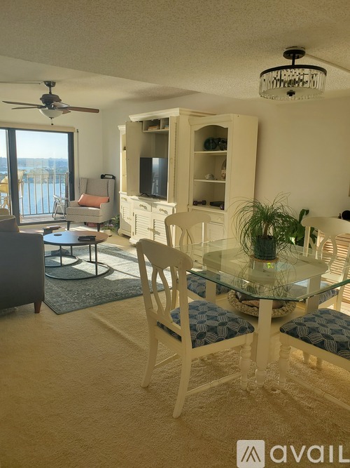 A living room with a glass table and chairs, a ceiling fan, and a television.
