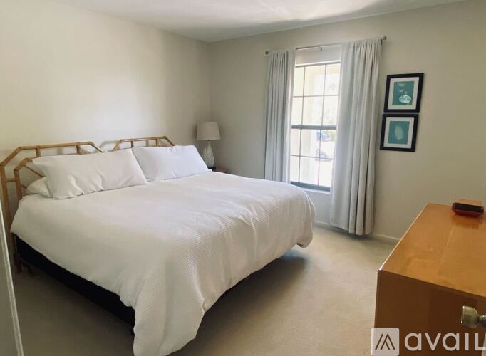 A bedroom with a large bed and a wooden nightstand.