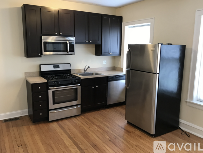 A kitchen with black cabinets and a stainless steel refrigerator.