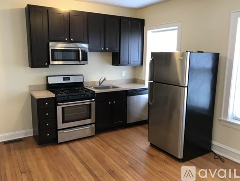 A kitchen with black cabinets and a stainless steel refrigerator.