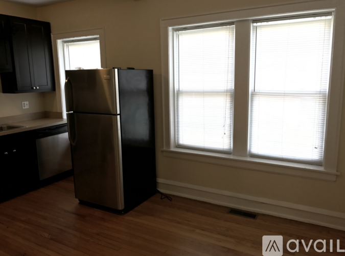A kitchen with a black fridge and wooden floors.