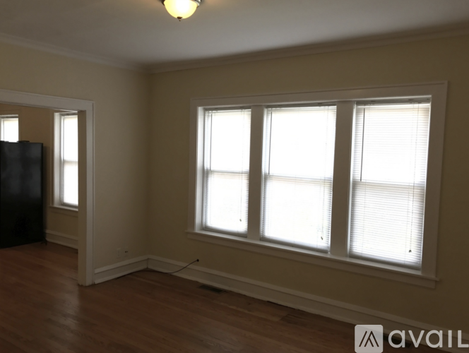 A room with a black refrigerator and wooden flooring.