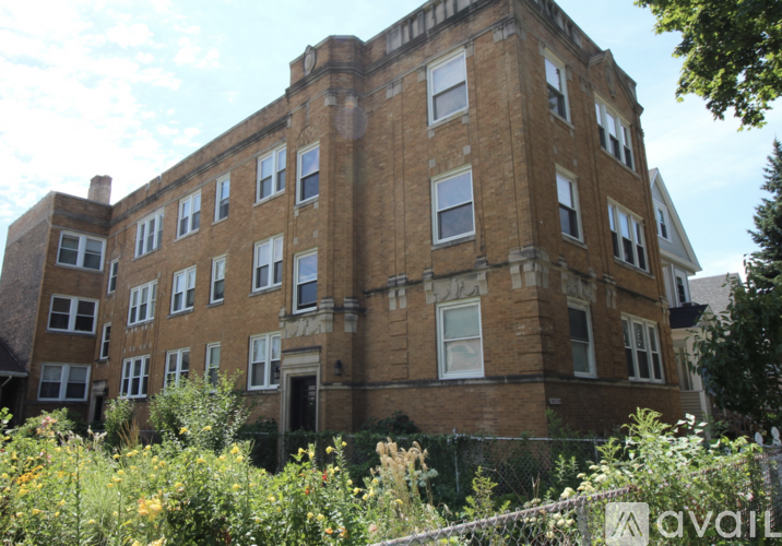 A large brick building with many windows and a fence in front.