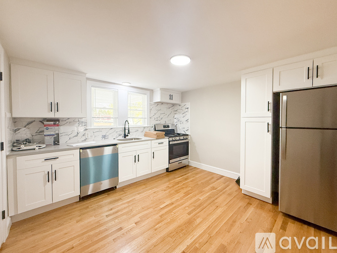 A kitchen with white cabinets and a wooden floor.