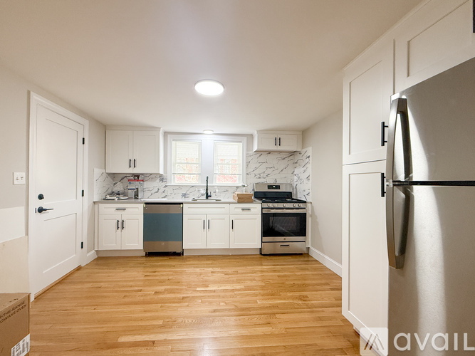 A kitchen with white cabinets and a wooden floor.