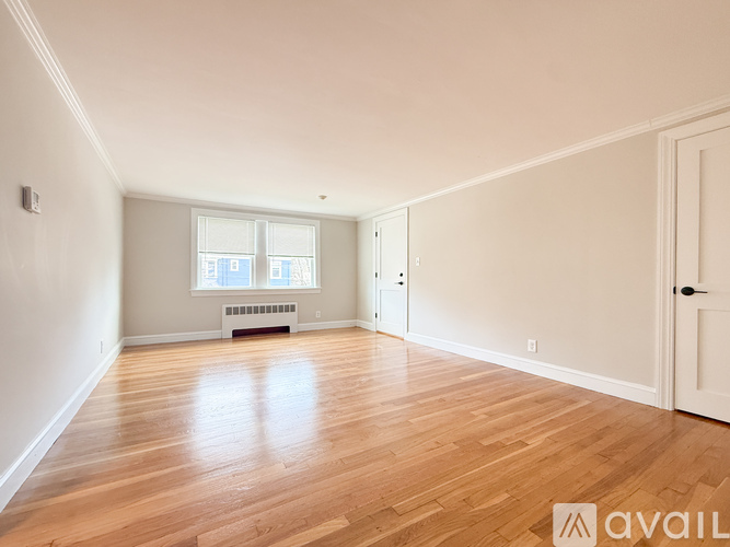 A spacious room with wooden flooring and white walls.