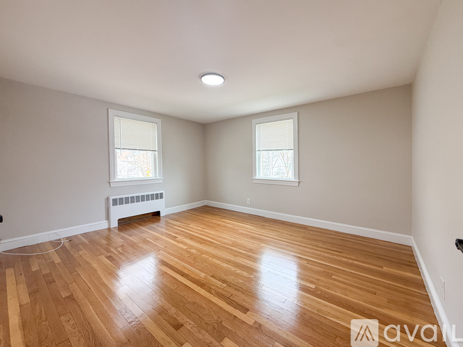A room with wooden floors and two windows.