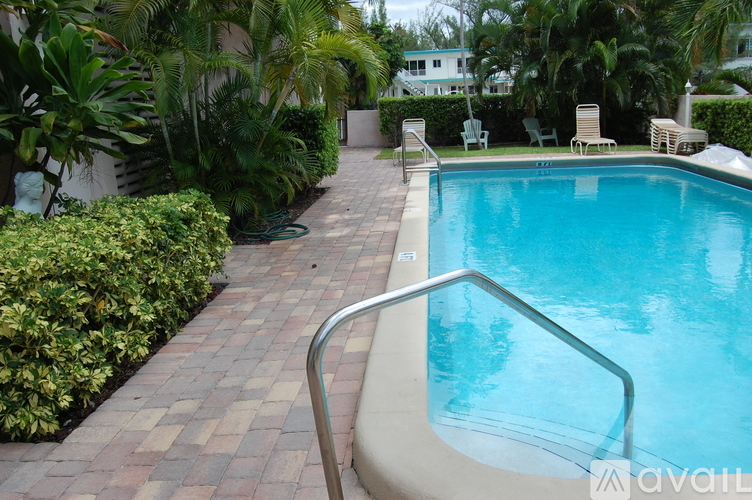 A pool surrounded by green plants and trees.