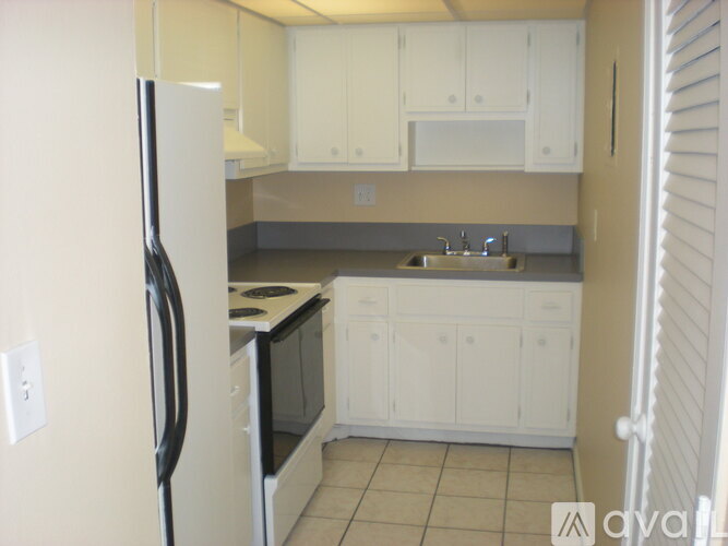 A kitchen with white cabinets and a black refrigerator.