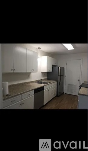 A kitchen with white cabinets and a wooden floor.