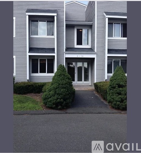 A grey building with a white door and windows.
