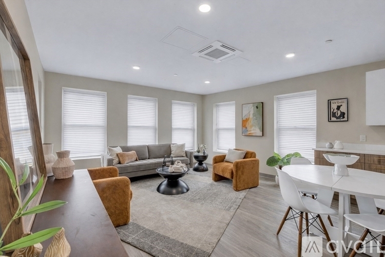 A well-lit living room with a brown wooden table and white chairs.