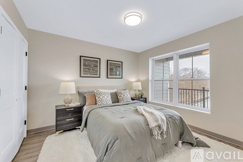 A bedroom with a large bed and a window overlooking a balcony.