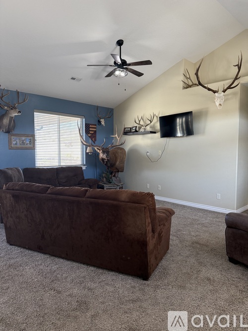 A living room with a brown couch and a ceiling fan.