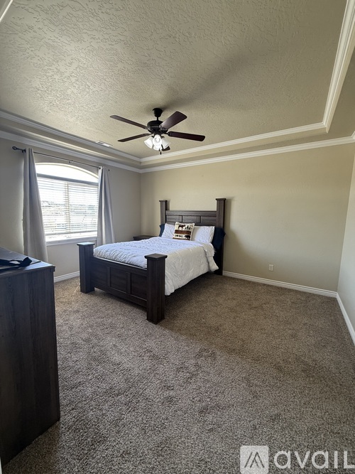 A bedroom with a bed, dresser, and window.