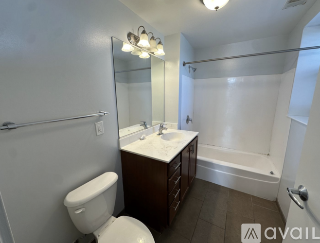 A bathroom with a toilet, sink, mirror, and bathtub.