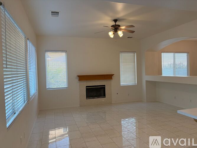 A spacious living room with a fireplace and a ceiling fan.