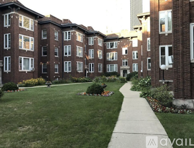 A brick apartment building with a well-kept lawn in front.