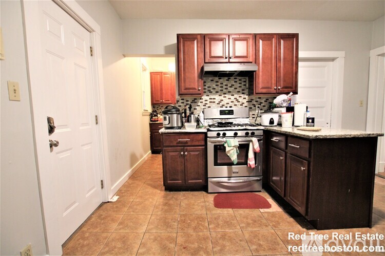 A kitchen with a stove top oven and a tiled backsplash.