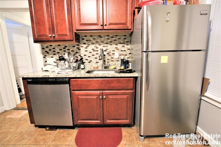 A kitchen with a stainless steel refrigerator and wooden cabinets.