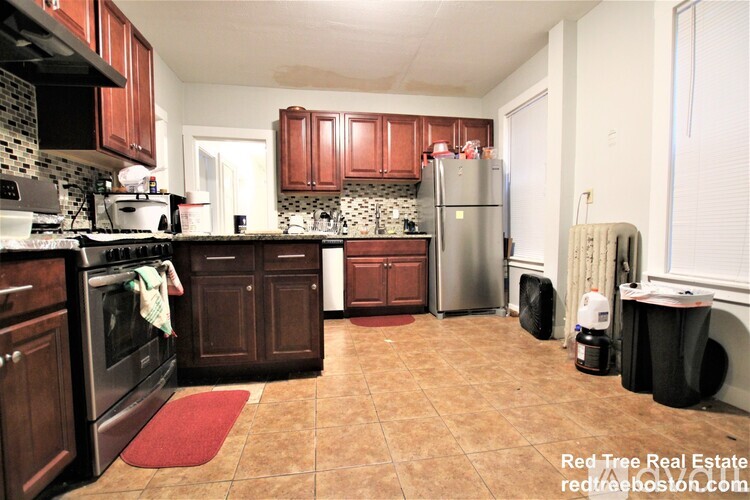 A kitchen with brown cabinets and a refrigerator.