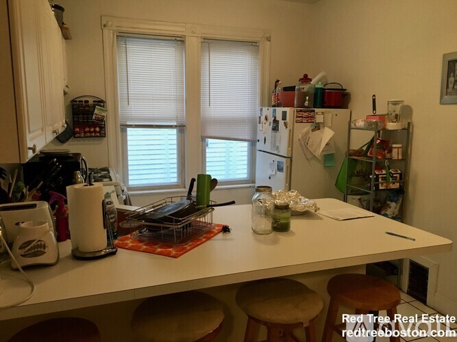 A kitchen with a white table and a refrigerator with many magnets on it.