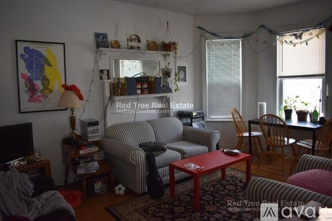 A living room with a grey couch and a red coffee table.