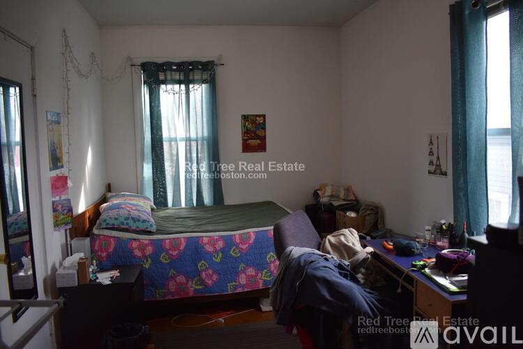 A bedroom with a bed, desk, and chair.