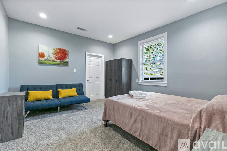 A bedroom with a bed, a couch, and a painting on the wall.