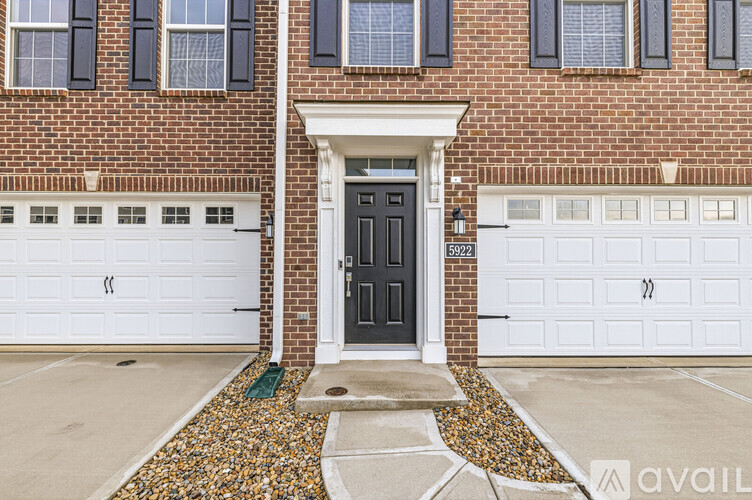 A brick house with a black front door and white garage doors.
