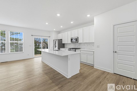 A kitchen with white cabinets and a wooden floor.