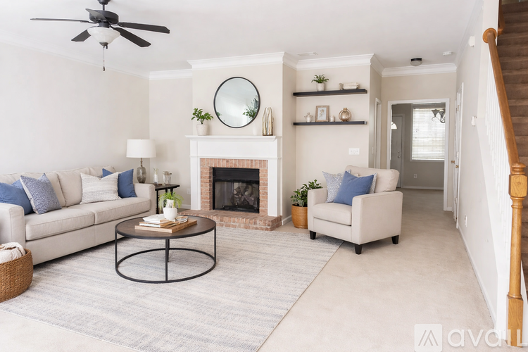 A living room with a fireplace, a couch, a chair, a coffee table, and a ceiling fan.