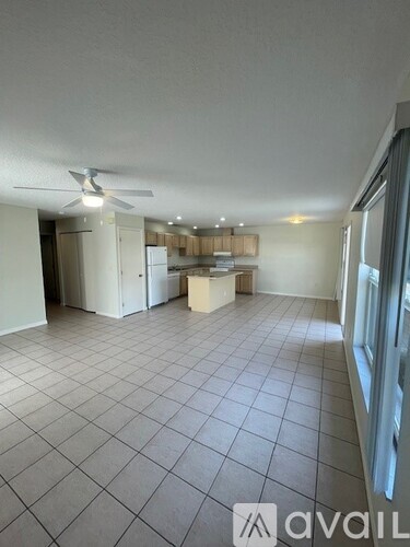 A spacious room with a fan and tiled flooring.
