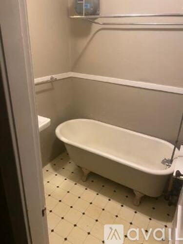A white bathtub with black dots on the floor.