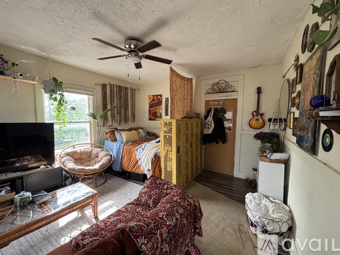 A living room with a couch, a chair, a television, and a guitar hanging on the wall.