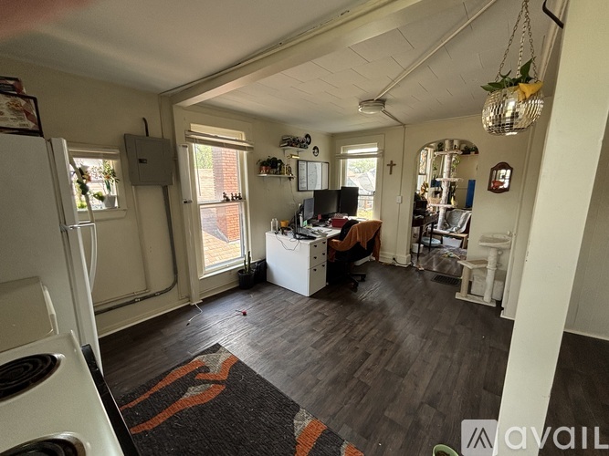 A kitchen with a refrigerator on the left and a dining table with chairs in the middle of the room.