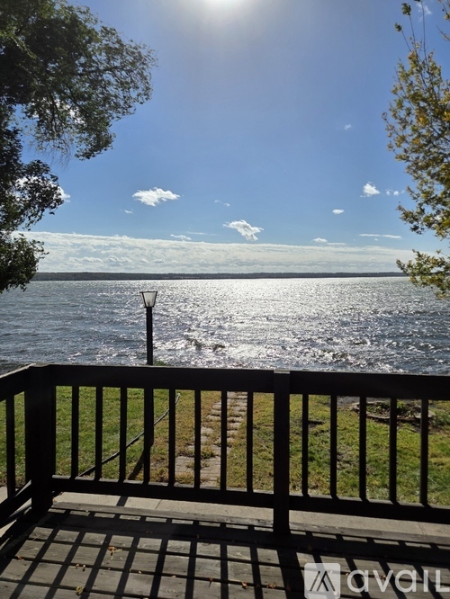 A sunny day at the lake with a black railing in the foreground.