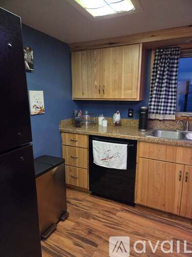 A kitchen with wooden cabinets and a black refrigerator.