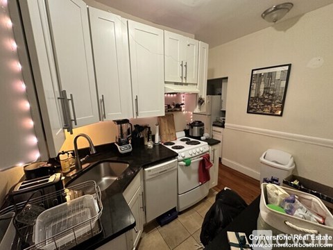 A kitchen with white cabinets and black countertops.