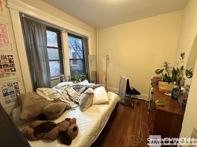 A small bedroom with a bed, a chair, and a desk.