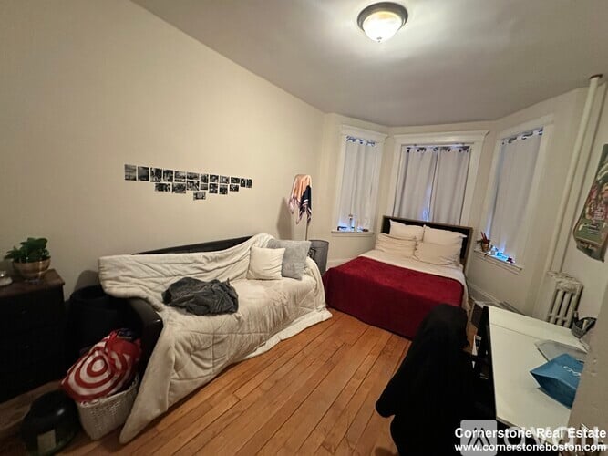 A bedroom with a bed, a couch, and a wall with pictures on it.