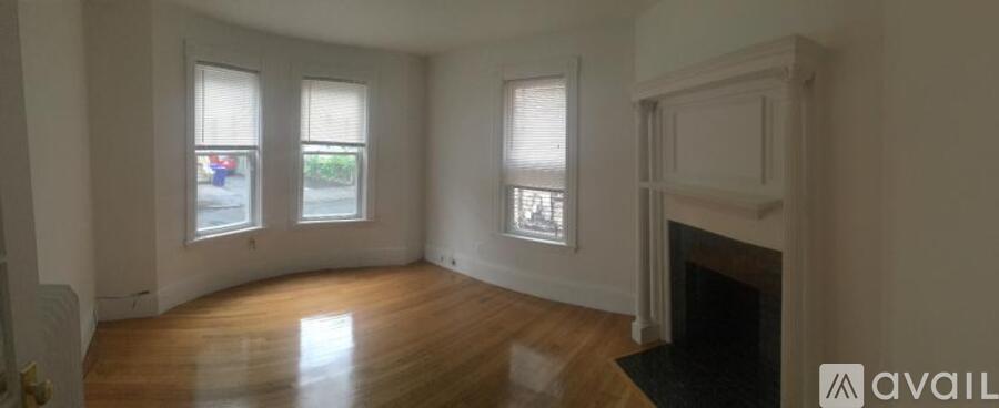 A large empty room with a fireplace and wooden floors.