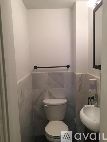 A white toilet in a small bathroom with a sink and mirror.