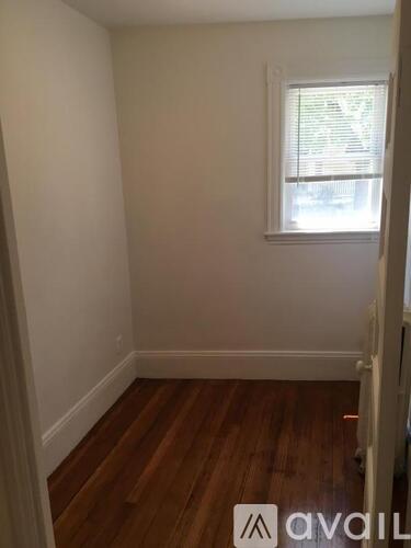 A room with wooden floors and a window with blinds.