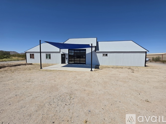A large white building with a blue roof is situated in a barren landscape.