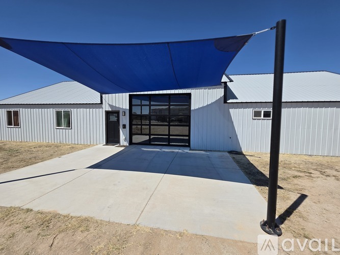 A white building with a blue shade structure in front.