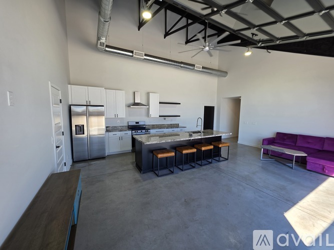 A modern kitchen with a purple couch in the living room.