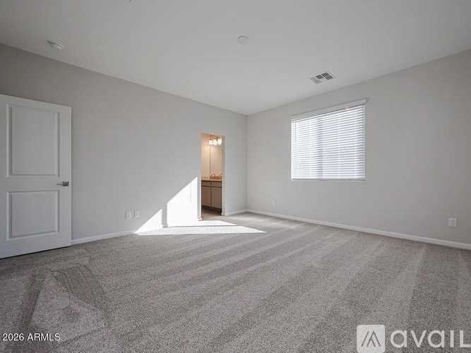 A spacious room with a carpeted floor and a door on the left.