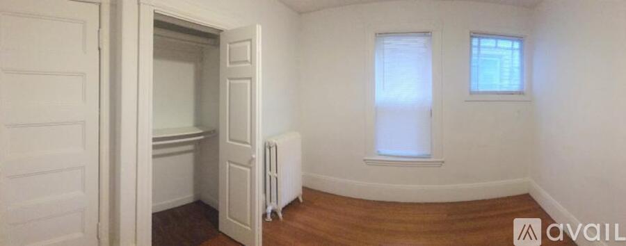 A room with a white door, a window, and a radiator.